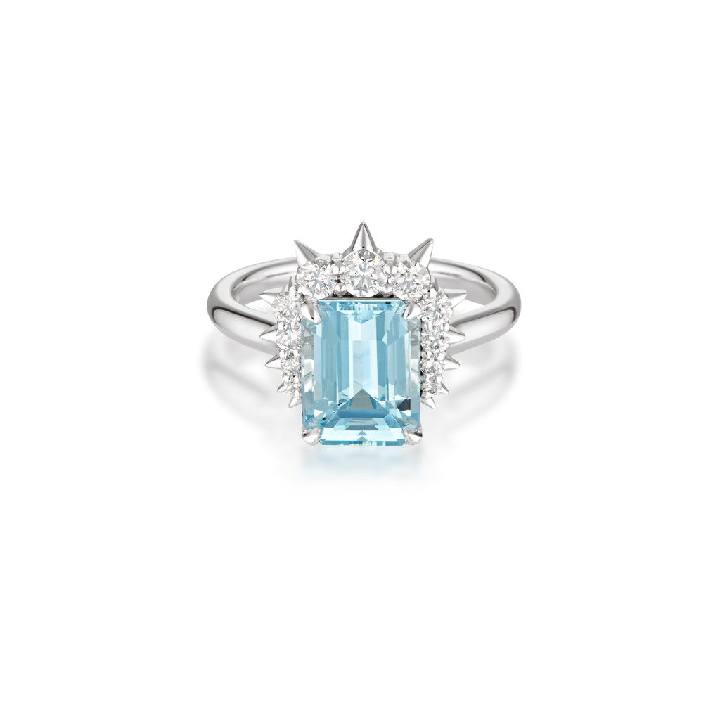 An elegant Alternative engagement ring with emerald-cut aquamarine gemstone surrounded by small diamonds, set on white gold band.