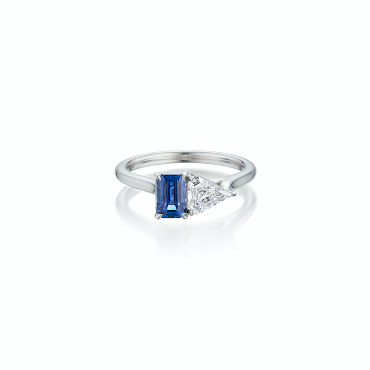 White gold ring with emerald-cut blue sapphire gemstone flanked up against a kite -shaped diamond.