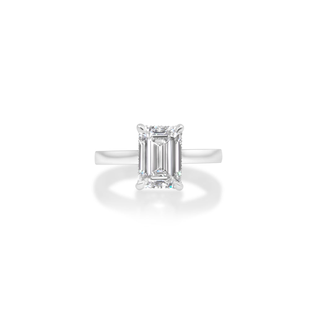 Emerald-cut diamond set in a simple band ring, isolated on a white background.