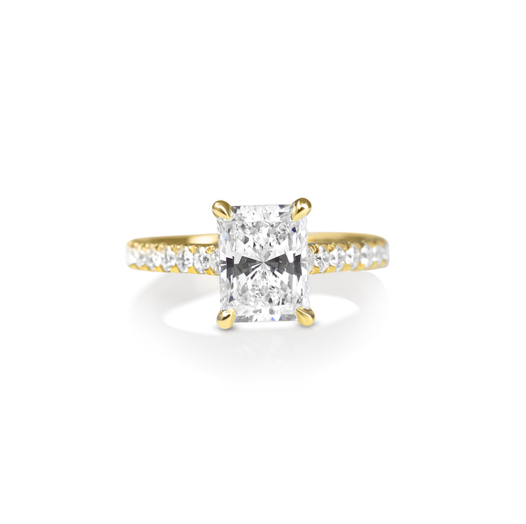 Gold ring with a central radiant-cut diamond and smaller diamonds on the band.