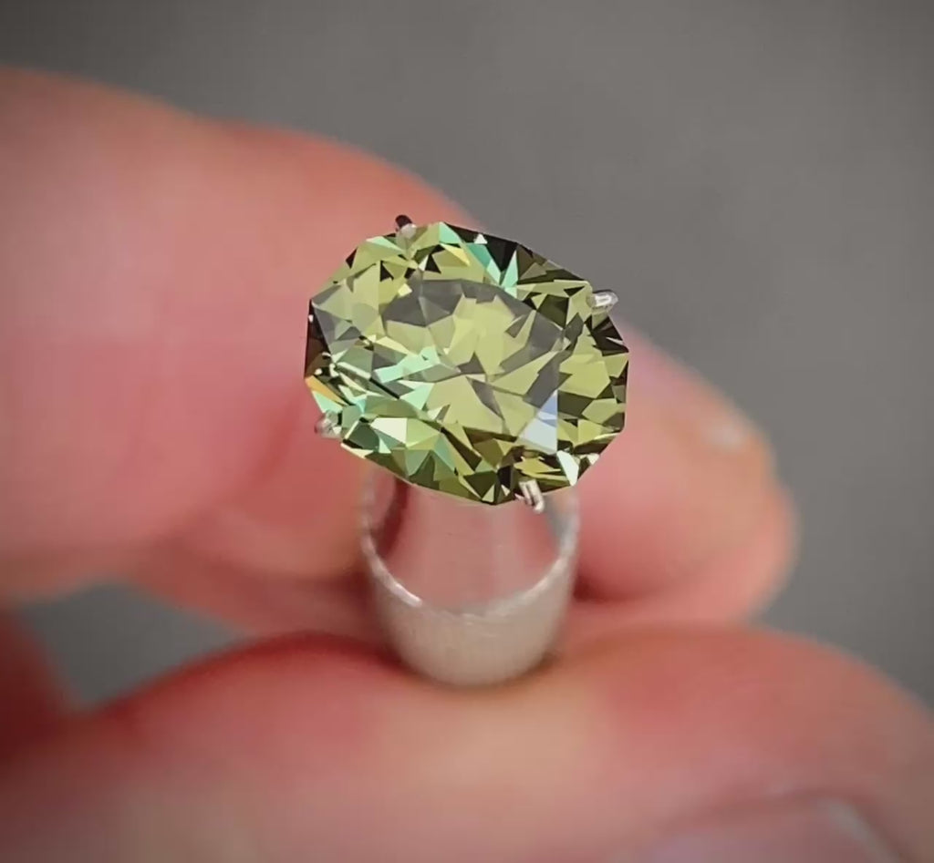 video of a oval shaped olive green Australian sapphire gemstone spinning back and forth