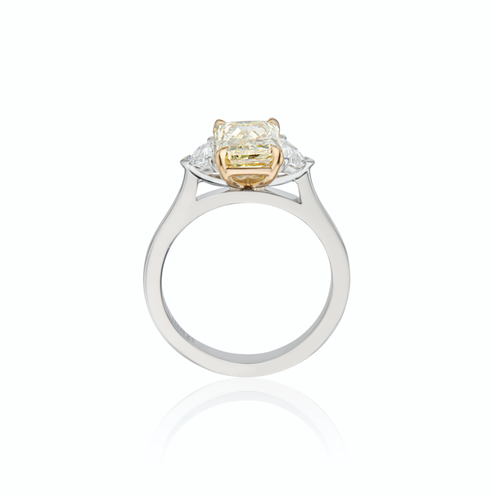 White gold ring with a large central yellow diamond flanked by smaller diamonds, isolated on a white background.