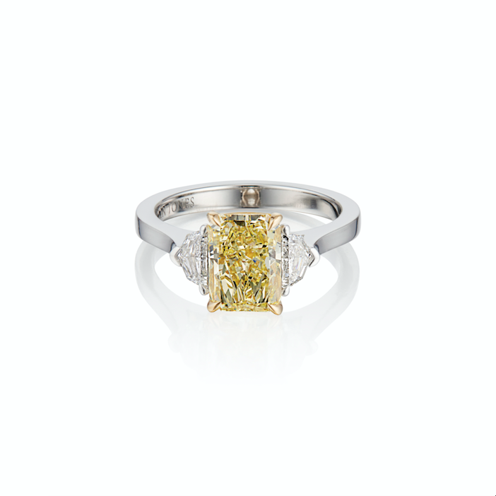 An elegant ring with a central yellow diamond flanked by two smaller clear diamonds.