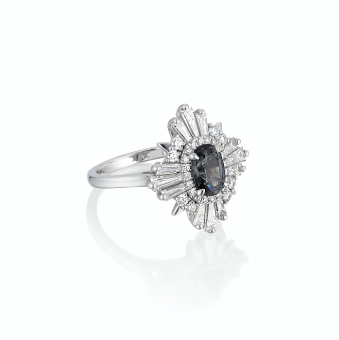 Elegant engagement ring showcasing a blue-gray spinel, complemented by tapered and round diamonds set in white gold.