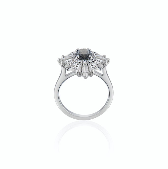 White gold ring standing upright with a blue/gray gemstone in centre and a cluster of diamonds surrounding.