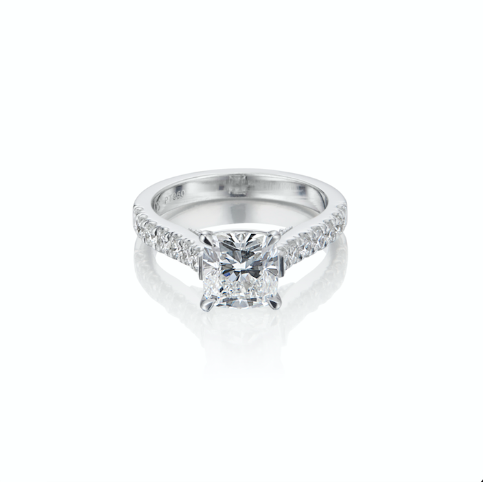 White gold diamond engagement ring with a central cushion-cut stone and smaller diamonds on the band.