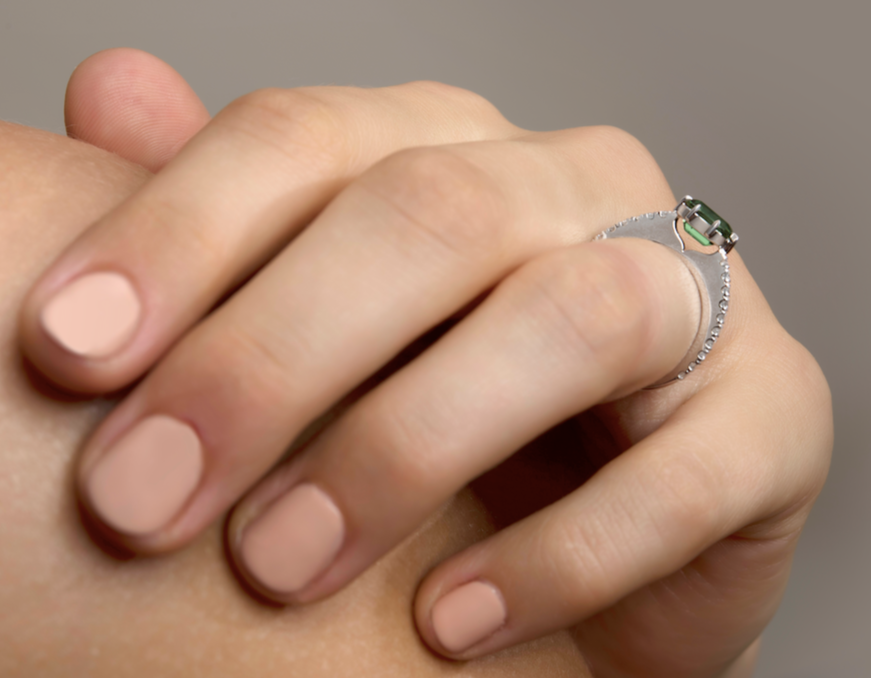 Close-up of a hand with painted nails wearing a ring with a green stone.