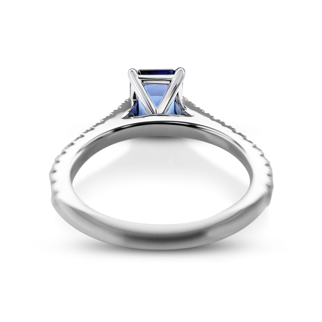 White gold ring with a blue gemstone in a prong setting, isolated on a white background.