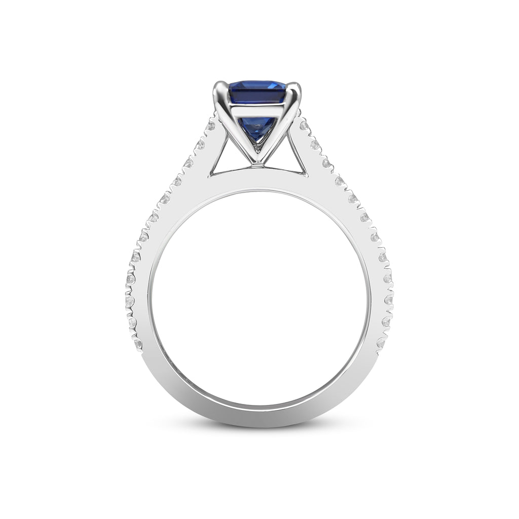 White gold ring with a blue sapphire set in a triangular mount and small diamonds along the band.