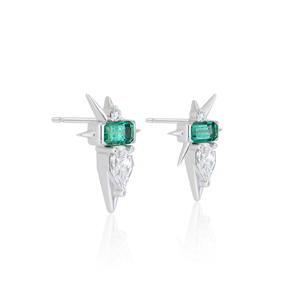 Pair of silver earrings with green emerald and diamond on white background.