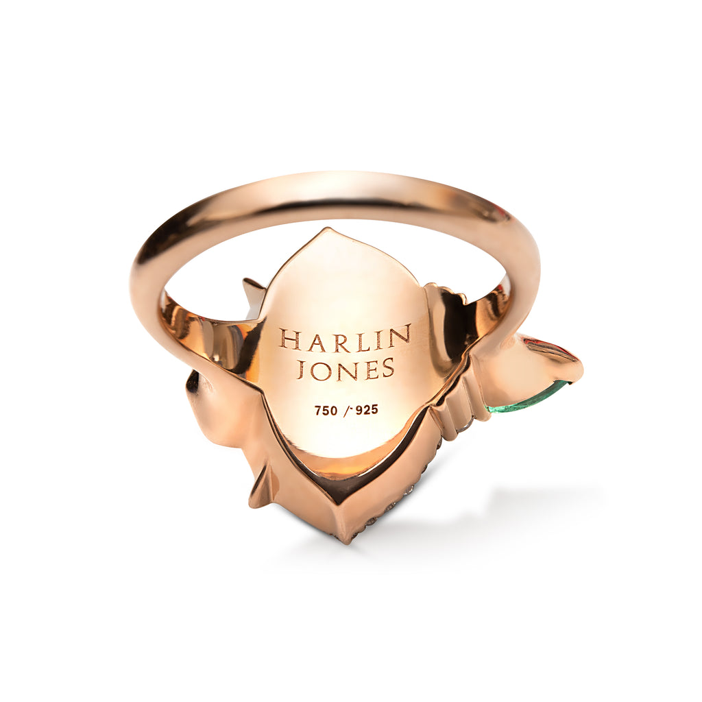 Rose gold ring with shield emblem and engraved text on a white background.