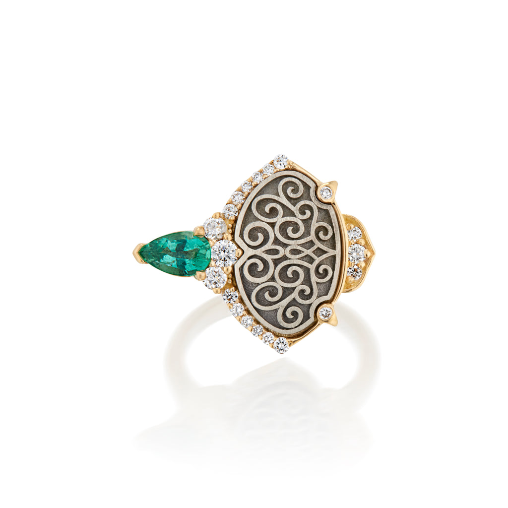 Gold ring with an emerald and diamond accents, featuring an intricate filigree design on a black background.