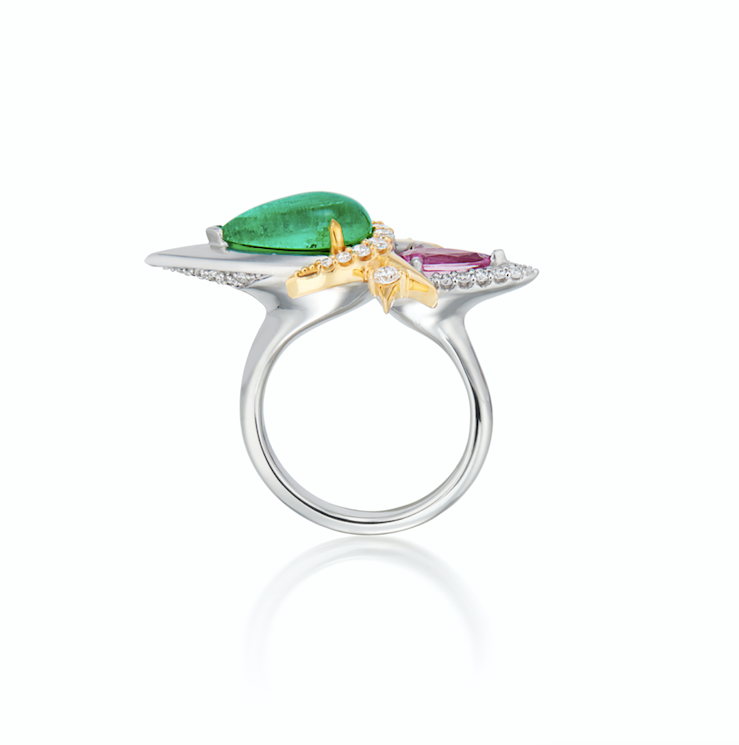 A silver ring with a large green emerald, smaller pink sapphire gemstone, and accent diamonds.