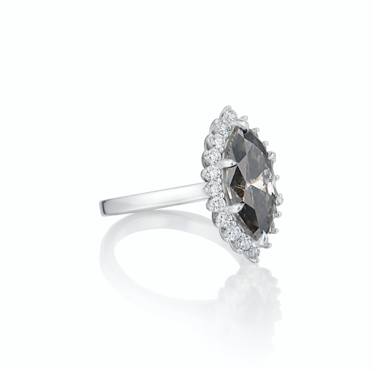 Grey diamond engagement ring surrounded by white diamond halo in white gold sitting sidways on white background