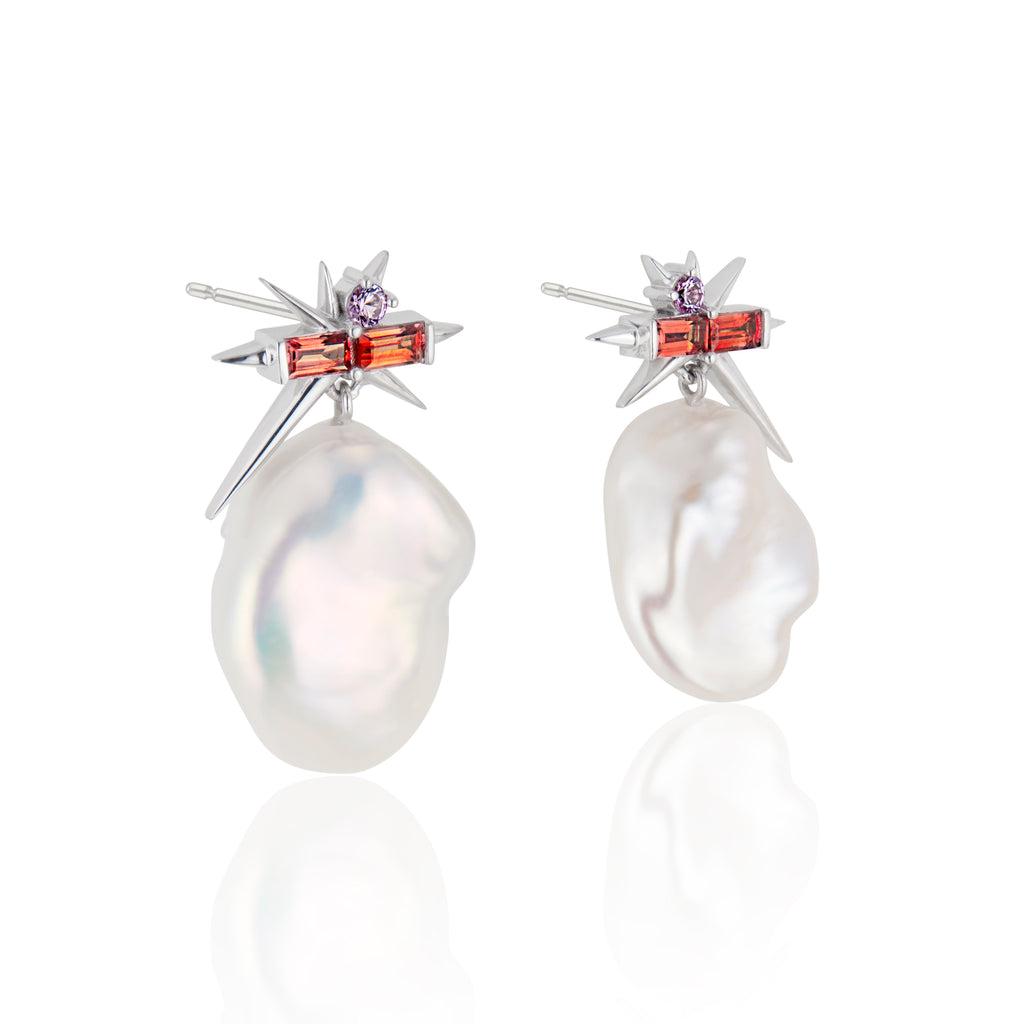 Pair of pearl earrings with orange and purple gemstone accents on white background.