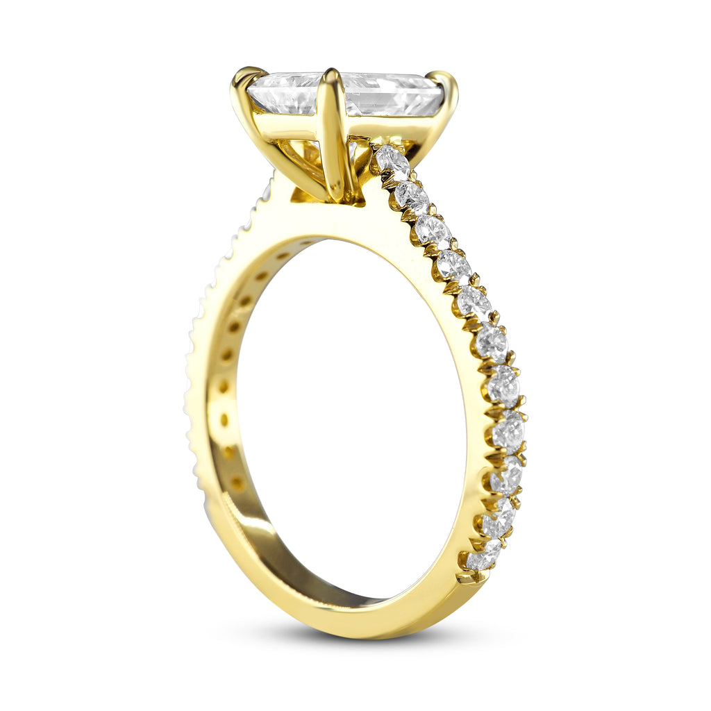 Gold engagement ring with radiant-cut diamond solitaire and encrusted side stones.