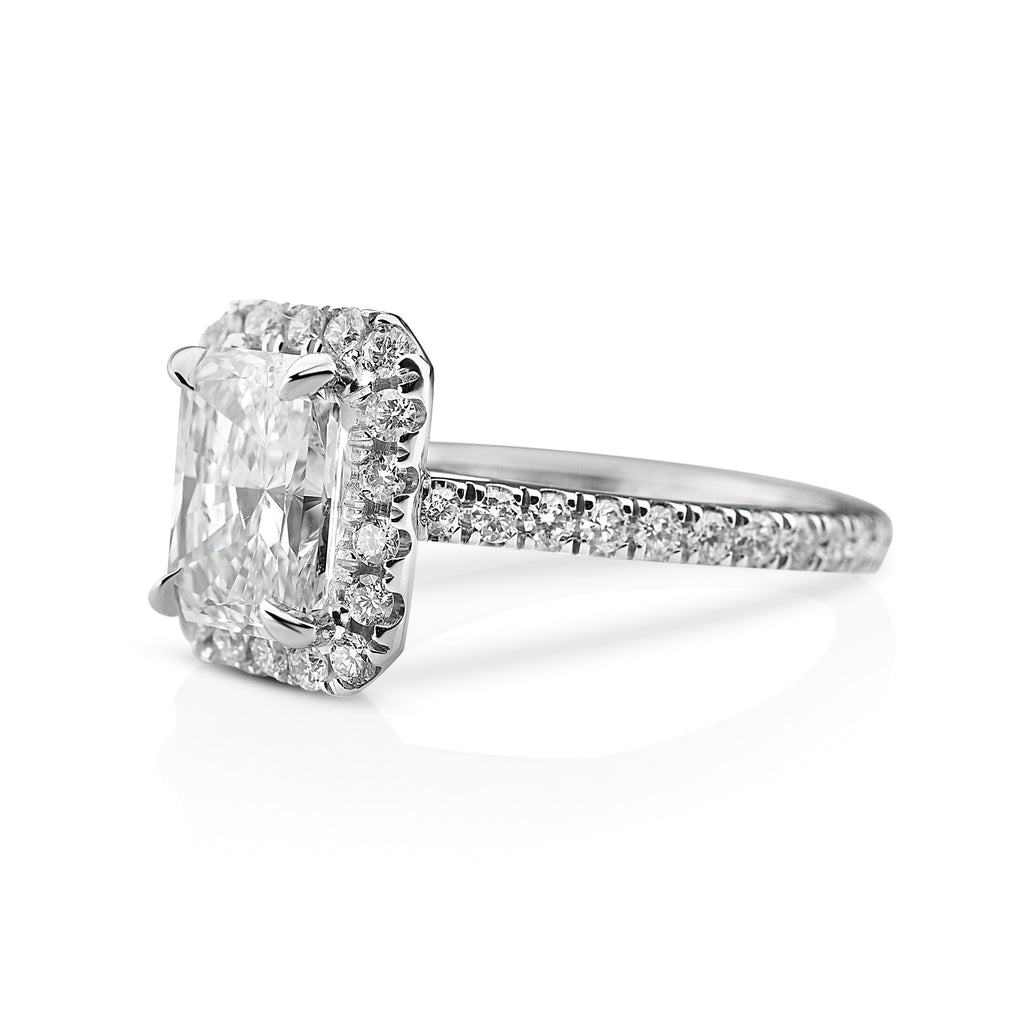 side view of elegant diamond ring with a large central radiant-cut diamond and encrusted diamond band on a white background.