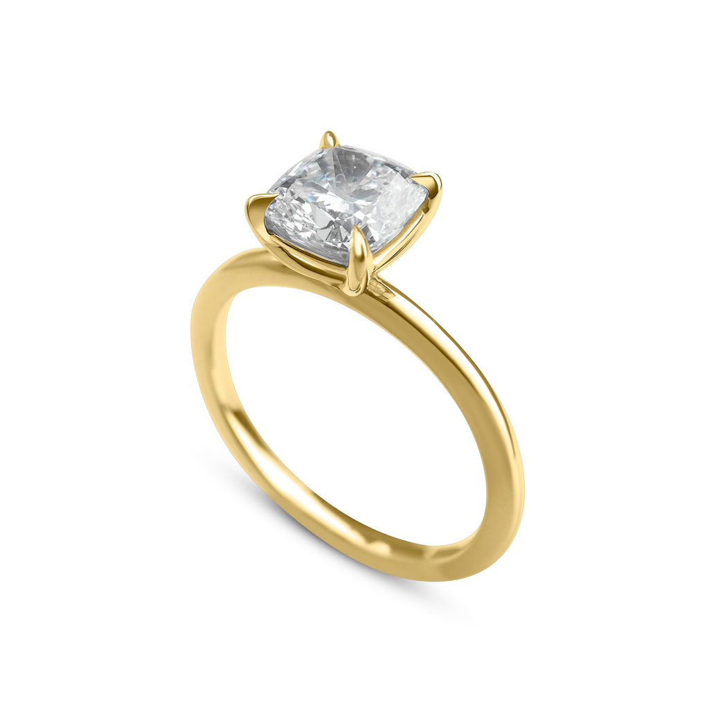 Thin gold ring with a single cushion-cut diamond standing upright on a white background