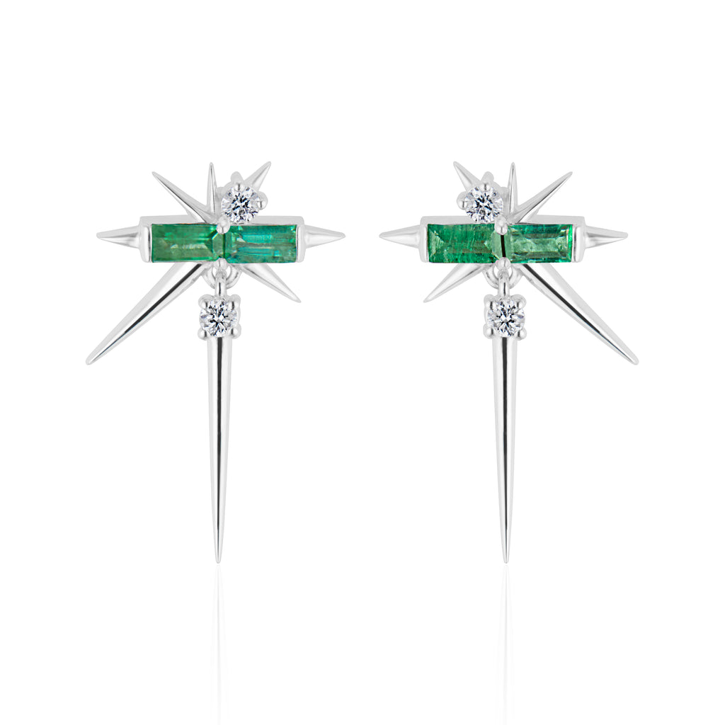 A pair of star-shaped silver earrings with green emerald gemstones and diamond accents.