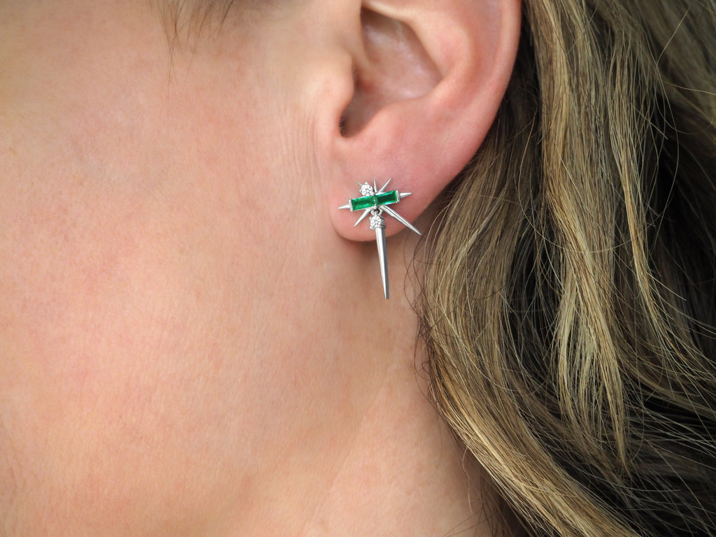 Close-up of a person's ear wearing a green and silver dragonfly earring.