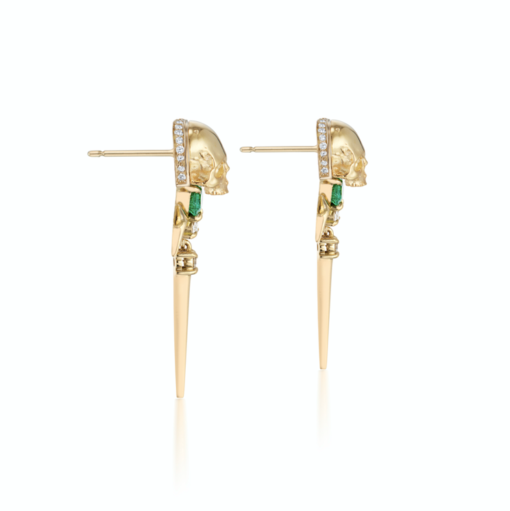 Gold spike earrings with skull detail, green gem eyes, and diamond accents.