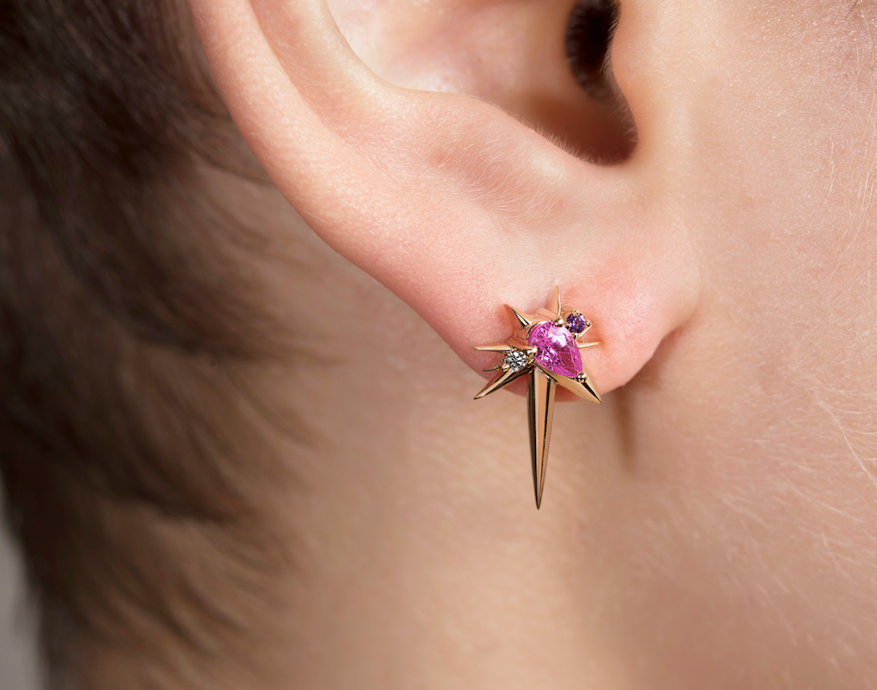 Close-up of an ear with a star-shaped earring with a purple gem.