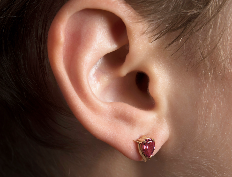 Close-up of an ear with a pink garnet stud earring.