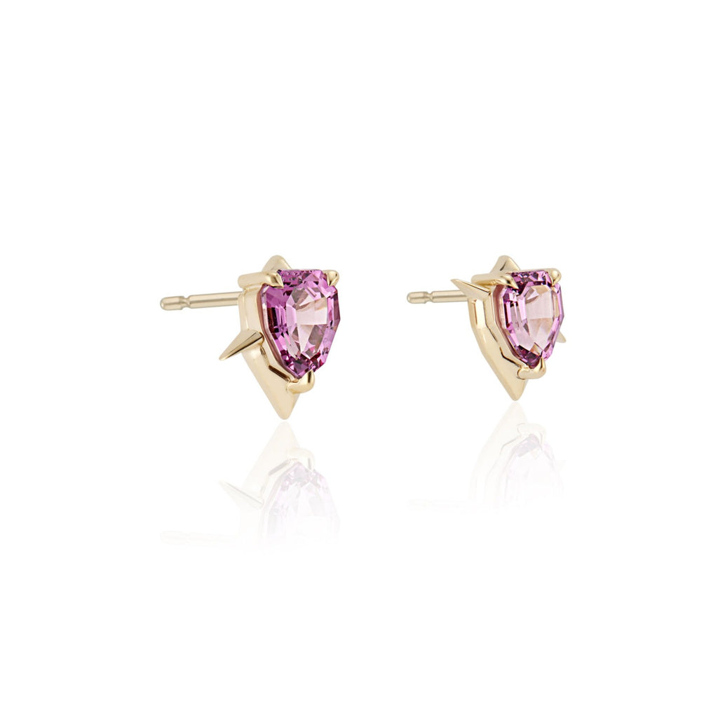 A pair of gold shield-shaped stud earrings with pink garnet gemstones, on a white background.