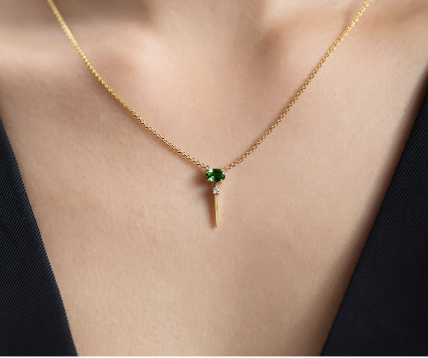 A necklace with a green gemstone pendant on a person's neck.